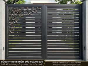 Cổng nan ngang có một cụm hồng leo ở góc trên, sơn đen nhám điểm nhũ